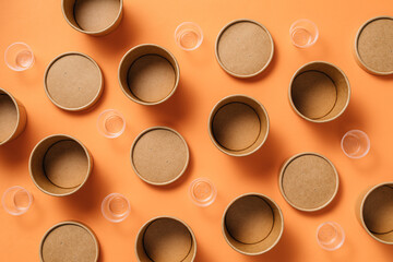 Top view composition of cardboard and plastic cups for takeaway food arranged on orange background