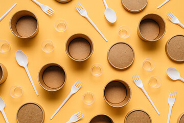 High angle of cardboard containers with plastic forks and spoons arranged with small plastic cups for takeaway food service on orange table