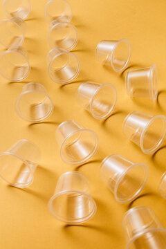 From above composition of small transparent disposable plastic cups for takeaway food service arranged on yellow background