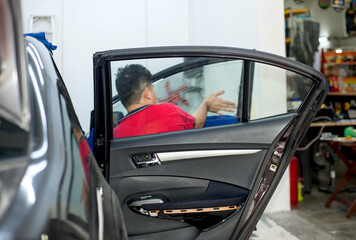 Penang, Malaysia - January 21, 2020 : Car window Tinting Specialist attaching Vinyl Tinting film to car side window.