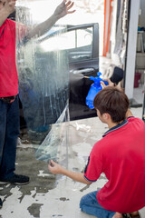 Penang, Malaysia - January 21, 2020 : 2 Car window Tinting specialist Spraying Soapy water on Vinyl Tinting Film.