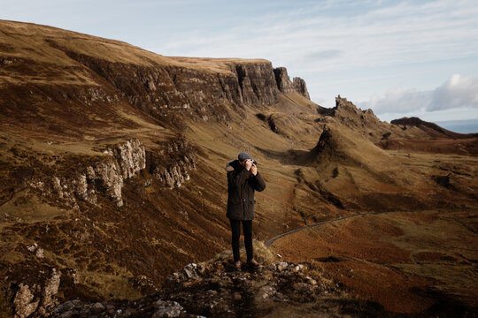 Anonymous male tourist with professional photo camera taking pictures of wonderful mountains in Scottish Highlands in fall