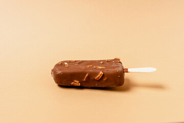 Ice cream on a stick in chocolate glaze on a brown background. Copy space.
