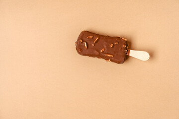 Ice cream on a stick in chocolate glaze on a brown background. Copy space.