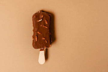 Ice cream on a stick in chocolate glaze on a brown background. Copy space.