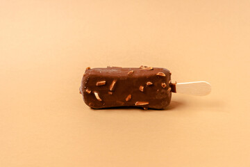 Ice cream on a stick in chocolate glaze on a brown background. Copy space.