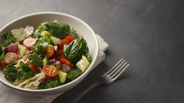 Juicy vegetable healthy salad with tomatoes, cucumbers, salad leaves in a beautiful plate, the camera moves to the side, place for text. close-up