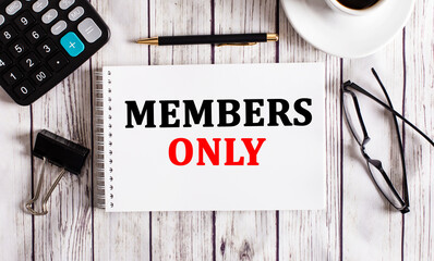The word MEMBERS ONLY is written in a white notepad near a calculator, coffee, glasses and a pen. Business concept