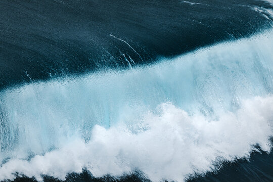 From above view of powerful blue breaking ocean waves with white foam