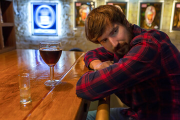 A lonely drunk man in depression sits at the bar in a bar. Alcoholism, crisis, alcoholism concept