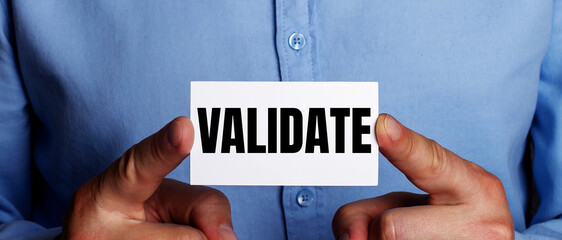 VALIDATE is written on a white business card in a man's hands. Business concept
