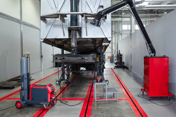 Servicing and repairing trucks in a large garage. Cargo trailer undergoing technical inspection at a car service. Car service, diagnostics