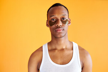 portrait of handsome afro american guy with patches for dark circles under eyes, young male do beauty procedures in the morning