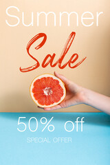 cropped view of woman holding juicy half of grapefruit near summer sale, fifty percent off, special offer lettering on beige and blue