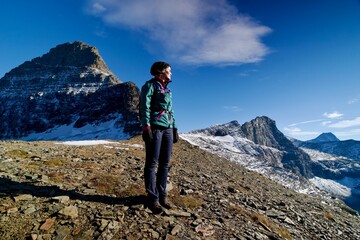 Fototapeta premium Young woman on top of dramatic mountaintop looking into distance