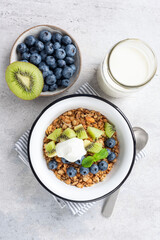 Granola with kiwi, blueberries and yogurt on concrete background. Healthy breakfast food, snack or vegetarian meal