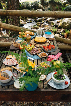 High angle of old wooden table with assorted dishes served for cozy picnic in forest in Valle del Jerte