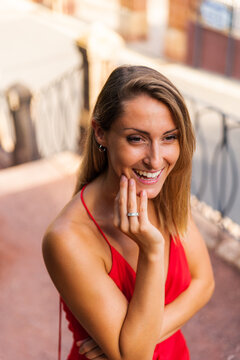 High angle of determined female wearing romantic red dress standing on stairs in city and looking away