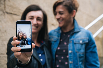 Happy middle aged lesbian couple showing a selfie in the smart phone