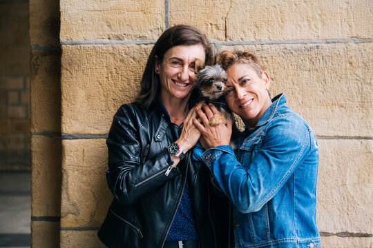 Happy middle aged lesbian couple hugging their yorkshire terrier