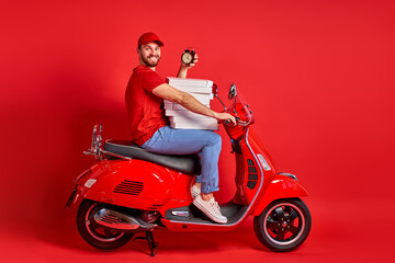 Obraz na płótnie Canvas studio shoot of young delivery man of takeaway on scooter with food case box driving fast, express food delivery service from cafes and restaurants. caucasian courier on the moto scooter isolated