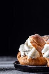 Homemade profitroles pastry filled with custard on dark background