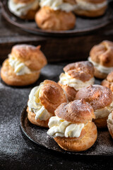 Homemade profitroles pastry filled with custard on dark background