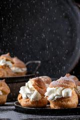 Homemade profitroles pastry filled with custard on dark background