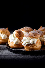 Homemade profitroles pastry filled with custard on dark background