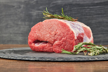 Raw beef steaks on wooden table with rosemary