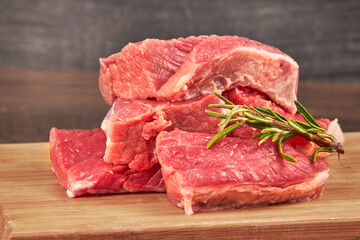Raw beef steaks on wooden table with rosemary