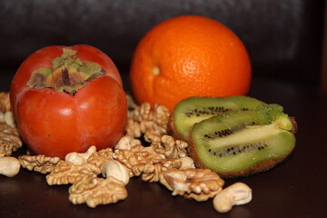 Sliced Green kiwi, persimmon and orange on a background of peeled walnuts