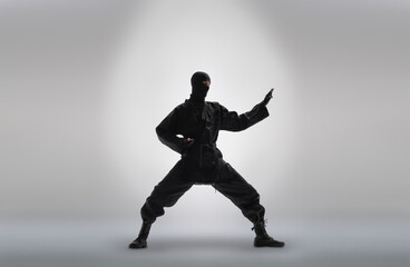 Fototapeta na wymiar japanese ninja in black uniform, on grey background