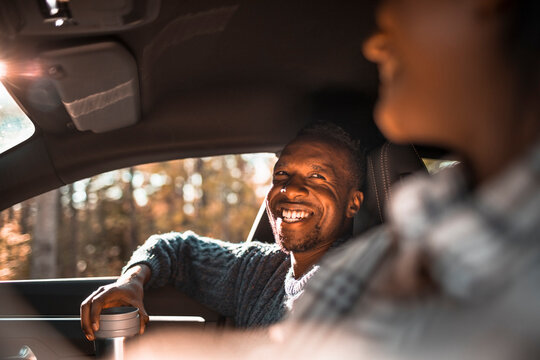 Smiling man looking at female friend in car during road trip