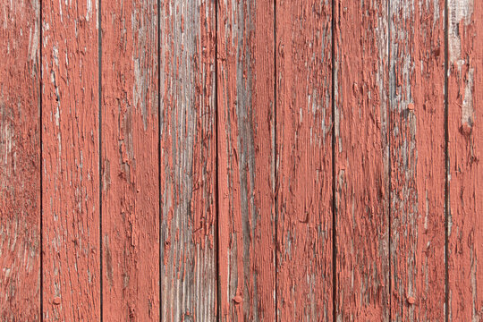 Red paint peeling off of old wooden boards on the side of a barn texture