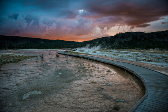 Scenic view of storm clouds over boardwalk passing through Biscuit Basin Geyser