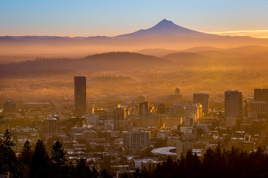 Scenic view of cityscape with silhouetted Mount Hood in background during sunrise