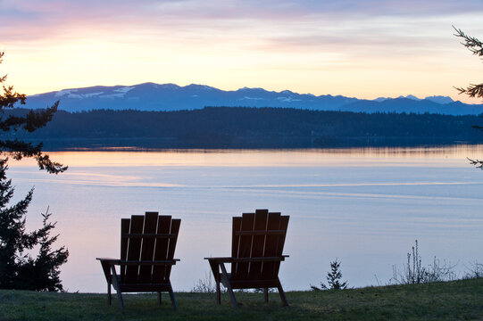 View of adirondack chairs on landscape by Puget Sound with North Cascades in background