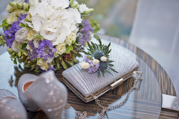 Composition of wedding items of the bride - bridal bouquet, handbag, shoes on the table. Overall plan. Selective focus.