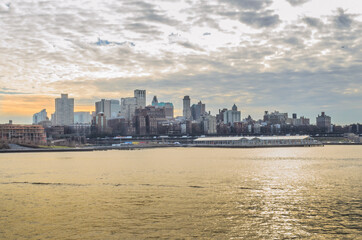 Fototapeta premium Brooklyn Borough Cityscape at Sunset. Beautiful Colors Reflected in the River and the Clouded Sky. New York City, USA