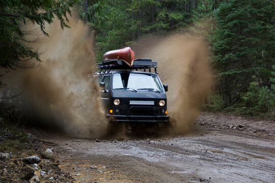 View of van driving through mud puddle on dirt road