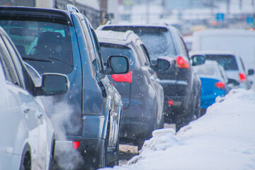 cars with brake lights on in a traffic jam in winter during snowfall