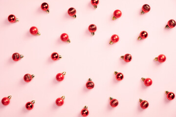 Red Christmas balls decoration on pastel pink background. Creative flat lay style composition, top view. Minimal style. Christmas, New Year, winter holiday poster, greeting card mockup.