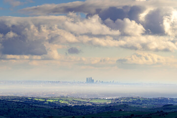 Skyline de la ciudad de Madrid en un día de niebla con cielo muy nublado y sol saliendo por el horizonte.