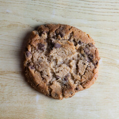 cookie with pieces of black and white chocolate on a wooden table.