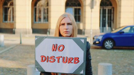 No disturb slogan on protest walk. Woman with steamer walking on the street.