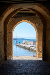 view through a medieval arch towards the sea in front of cefalu