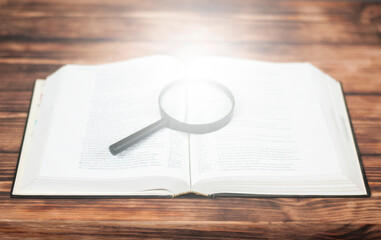 Open Bible book on a wooden table. Light from a book. Magnifier on the book. Close-up.