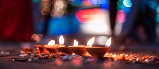 Closeup of lit Diya on Diwali against bokeh of string lights in the background at night.