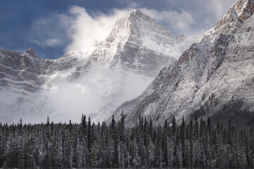 Fototapeta na wymiar A snowstorm clears over Howse Peak along Icefields Parkway, above Chephren Lake, on the continental divide in Alberta, Canada. A beautiful, snowy mountain scene. 